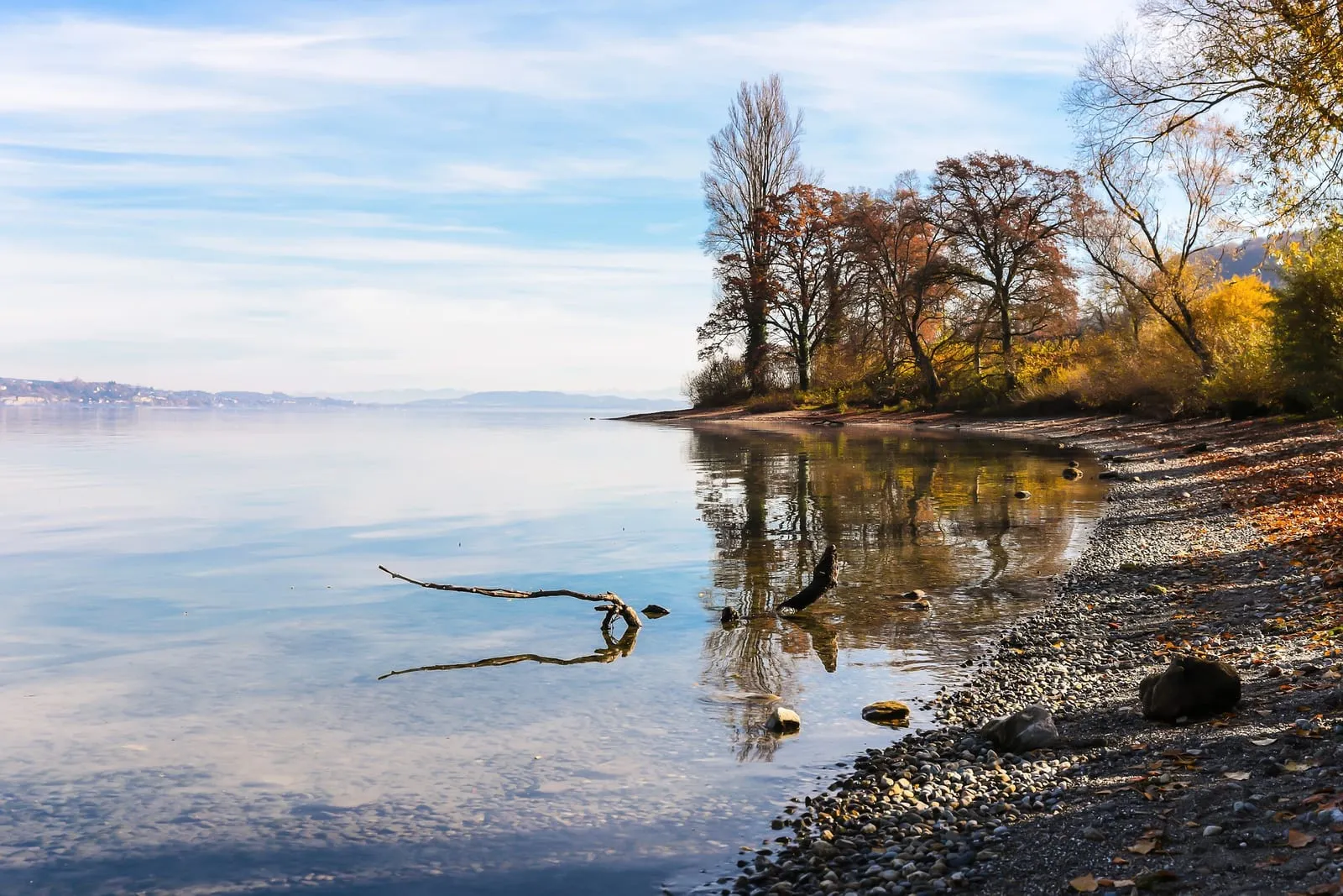 Kiesstrand am Bodensee-Ufer mit Blick über das Wasser im Herbst