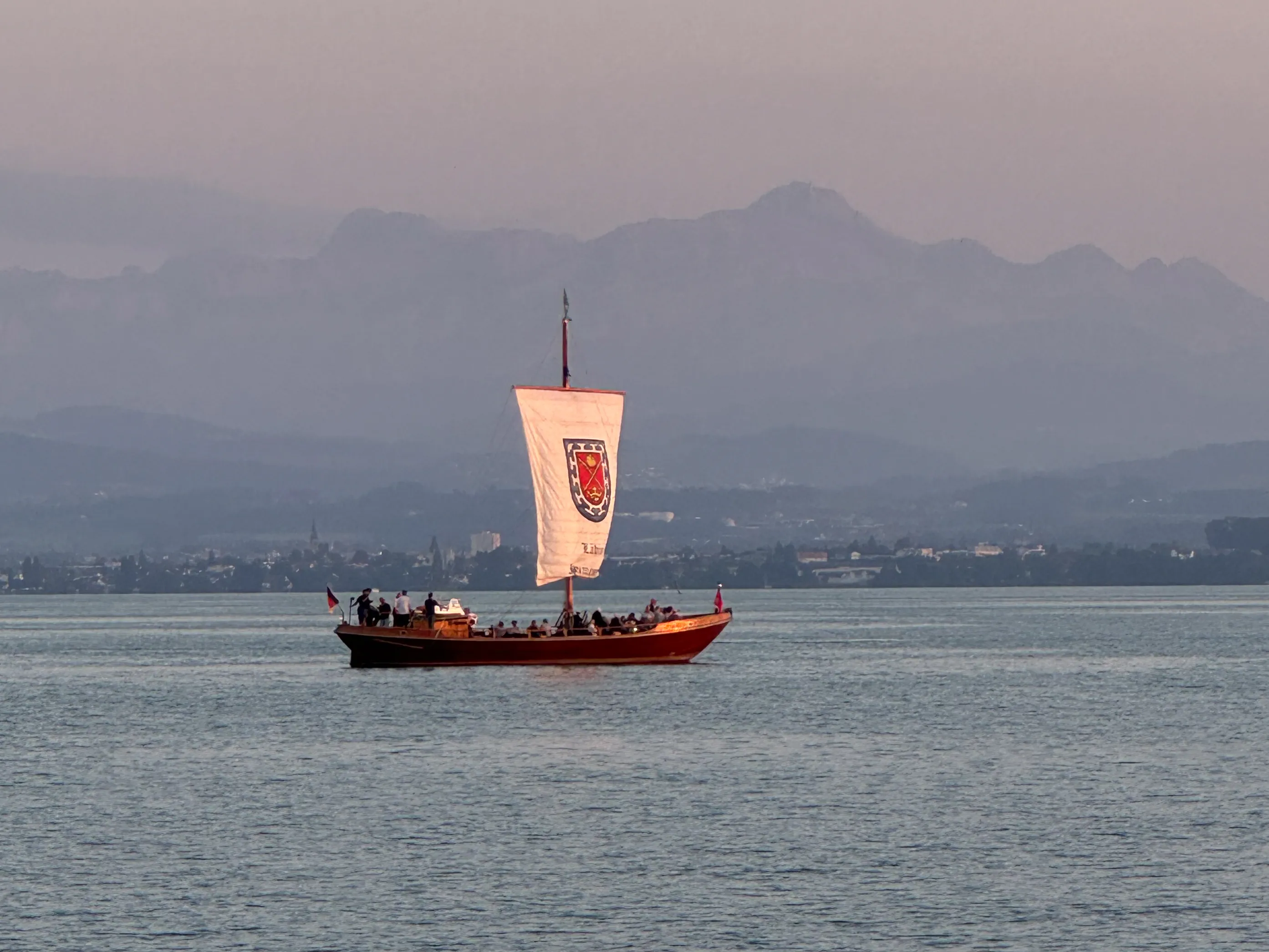 Die historische Lädine St. Jodok unter Segel auf dem Bodensee vor den Alpen bei Immenstaad